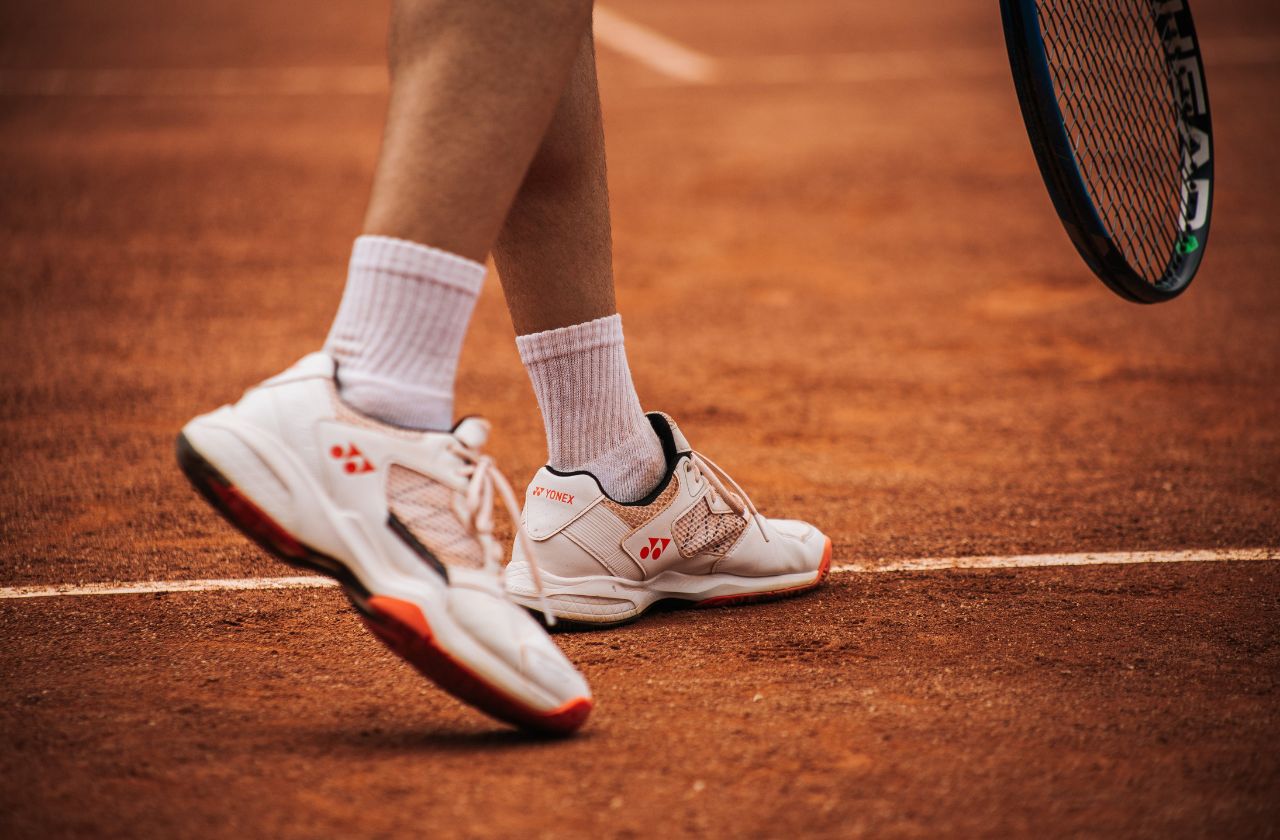 Tennis shoes provide lateral stability and cushioning to reduce impact and injury risk during rapid direction changes