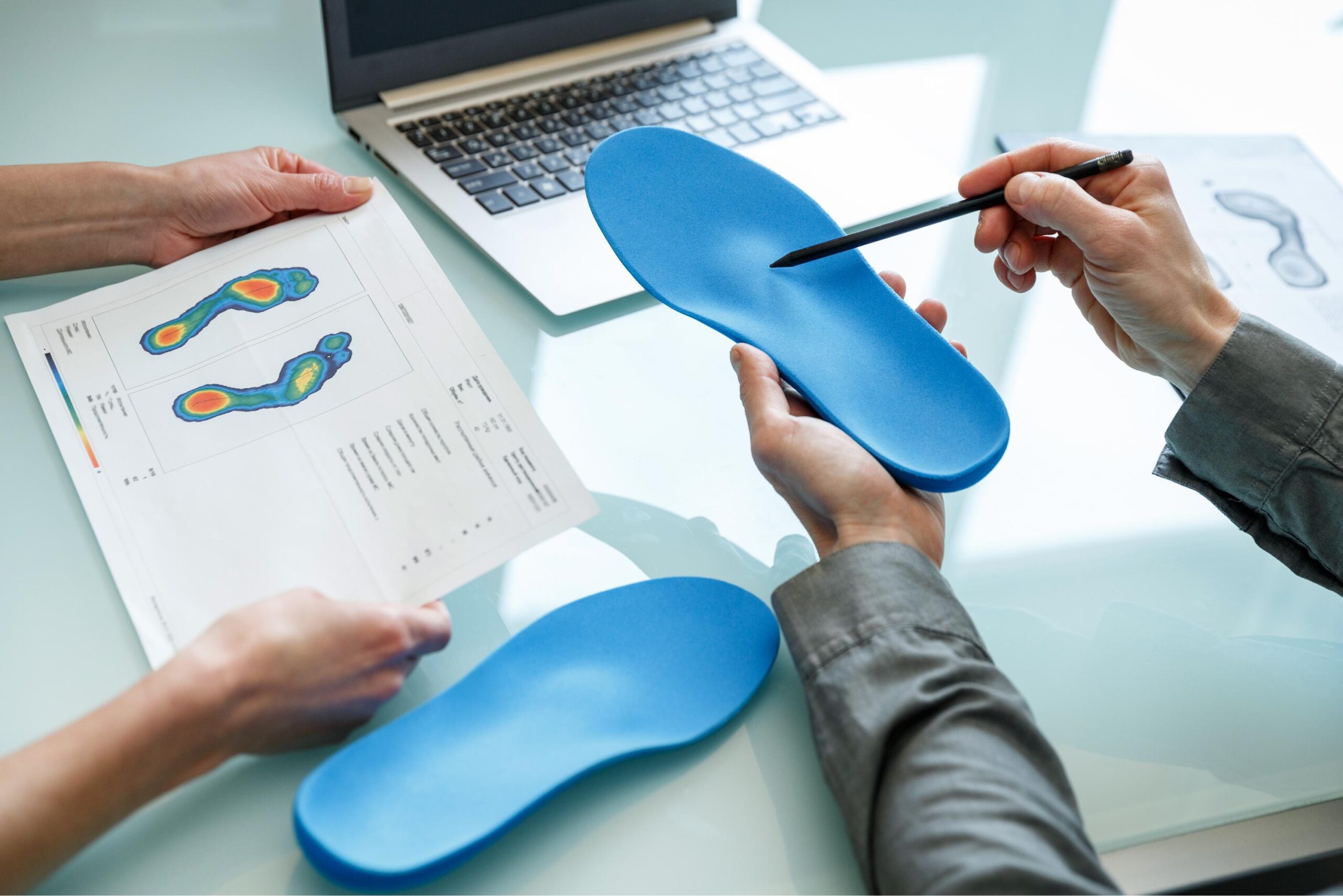 A podiatrist looking at scans of weight distribution in a patients foot and comparing it to their custom orthotics to ensure they are correct for the patient.