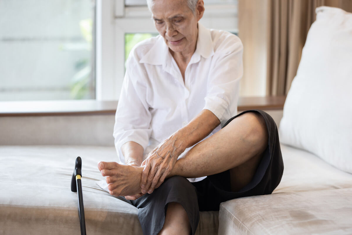 Senior man rubbing his feet awaiting one of our mobile podiatry team to arrive at his home.